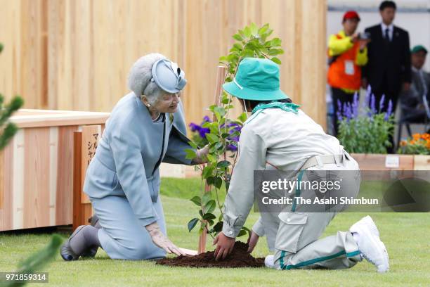 Empress Michiko plants a young tree with a child during the National Tree-Planting Festival on June 10, 2018 in Minamisoma, Fukushima, Japan. This...