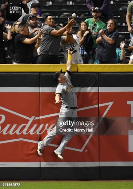 Corey Dickerson of the Pittsburgh Pirates crashes into the left field wall and cannot make a catch on a three run home run by Jake Lamb of the...