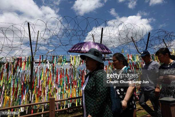 Visitors walk past prayer ribbons wishing for reunification of the two Koreas on the wire fence at the Imjingak Pavilion, near the demilitarized zone...