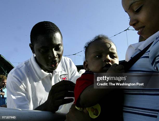 Kevin Clark\ The Washington Post Neg #: 156645 Rochester, NY Freddy Adu signs the shirt of Paul Calvin, 5 months, with mom Amaryllis Figueroa holding...