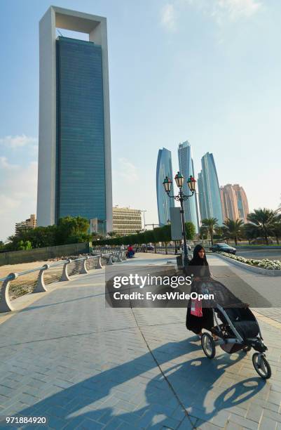 Woman with a baby buggy between skyscrapers at Saadiyat Island on November 27, 2015 in Abu Dhabi, Emirate Abu Dhabi.