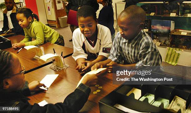 Photog: Gerald Martineau Jefferson-Houston Elem. School Alex, VA neg: 152139 kids run credit union Fourth grader Corretta Wright, left, hands a...
