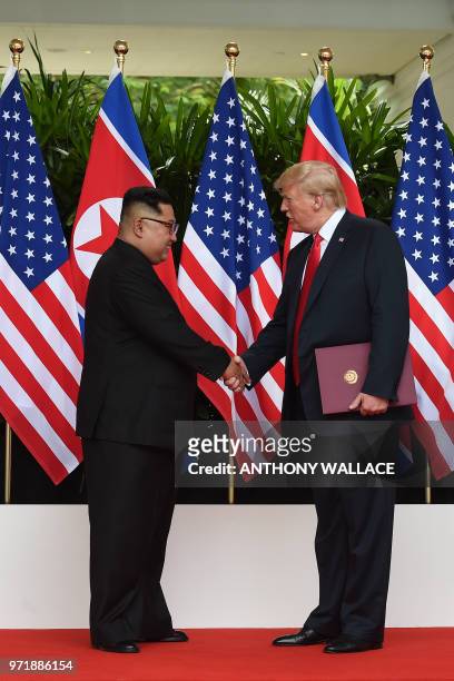 North Korea's leader Kim Jong Un shakes hands with US President Donald Trump after taking part in a signing ceremony at the end of their historic...