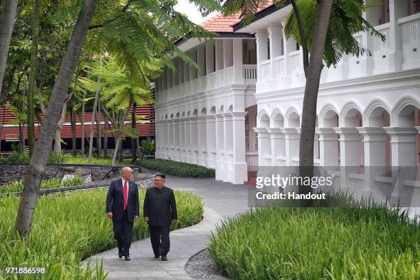 In this handout photograph provided by The Strait Times, U.S. President Donald Trump with North Korean leader Kim Jong-un with during their historic...