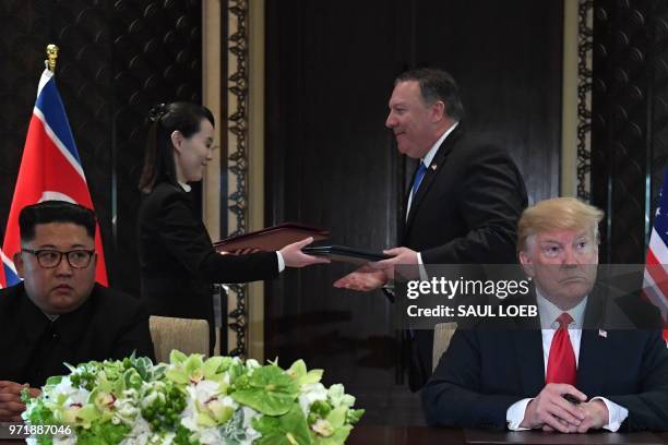 President Donald Trump and North Korea's leader Kim Jong Un look on as documents are exchanged between US Secretary of State Mike Pompeo and the...