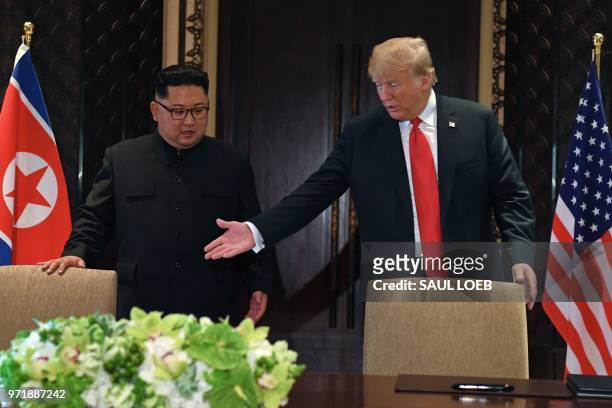 President Donald Trump gestures as he and North Korea's leader Kim Jong Un arrive for a signing ceremony during their historic US-North Korea summit,...