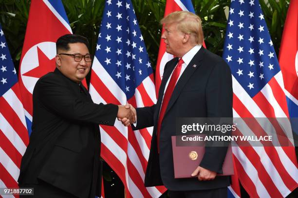 North Korea's leader Kim Jong Un shakes hands with US President Donald Trump after taking part in a signing ceremony at the end of their historic...