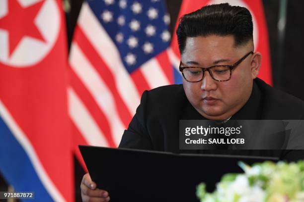 North Korea's leader Kim Jong Un looks at his document at a signing ceremony with US President Donald Trump during their historic US-North Korea...