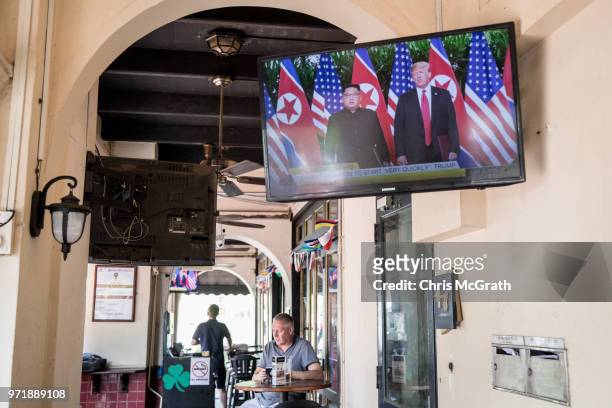 Tv screen at a bar replays footage of the meeting between U.S. President Donald Trump and North Korean leader Kim Jong-un on June 12, 2018 in...