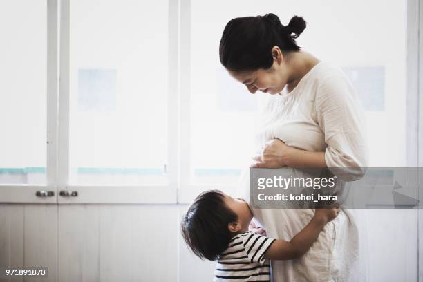 schwangere frau und sohn entspannt zu hause - asian woman pregnant stock-fotos und bilder