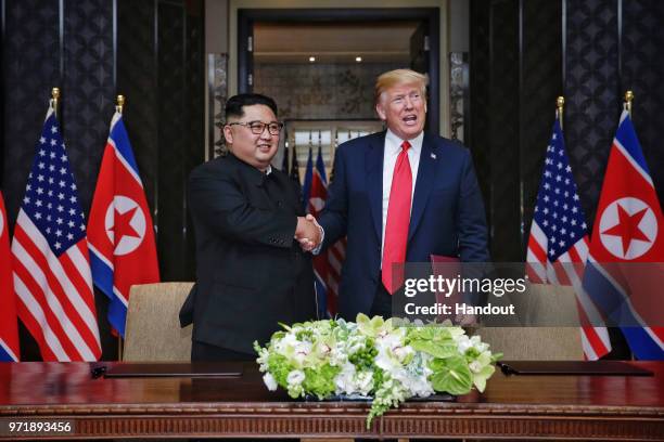 In this handout photograph provided by The Strait Times, North Korean leader Kim Jong-un with U.S. President Donald Trump during their historic...