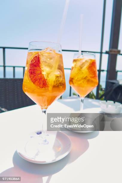 Italian Aperitif - two glasses of Aperol Sprizz drink at the terrace of a sunny cafe in the historic center on April 8, 2018 in Taormina, Sicily,...