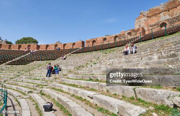 People sitting on the stairs of Teatro Greco, the ancient greek theatre on April 8, 2018 in Taormina, Sicily, Italy.