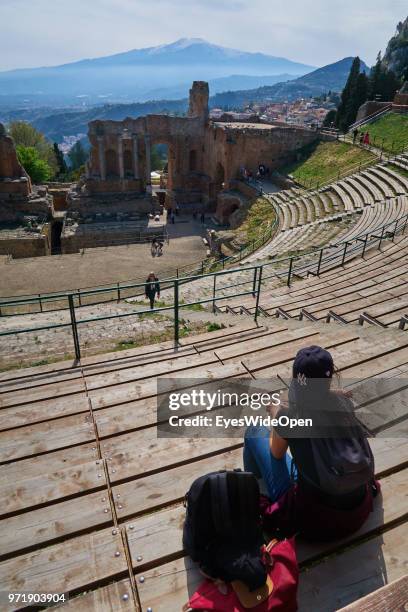 People in the Teatro Greco, the ancient greek theatre that is facing Mount Etna on April 8, 2018 in Taormina, Sicily, Italy.