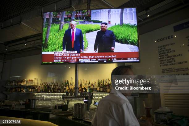 Screen displays a news broadcast of U.S. President Donald Trump and North Korean leader Kim Jong Un attending the DPRK-USA Singapore Summit, at a...