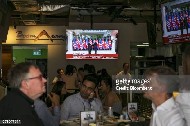 Screen displays a news broadcast of U.S. President Donald Trump and North Korean leader Kim Jong Un shaking hands at the DPRK-USA Singapore Summit,...