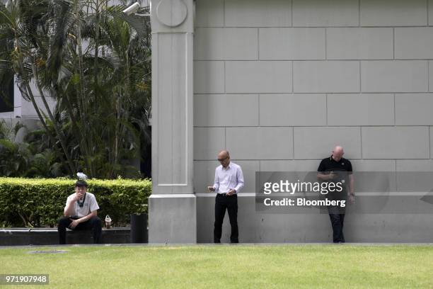 Men smoke cigarettes and use mobile phones in Singapore, on Tuesday, June 12, 2018. U.S. President Donald Trump and North Korean leader Kim Jong...