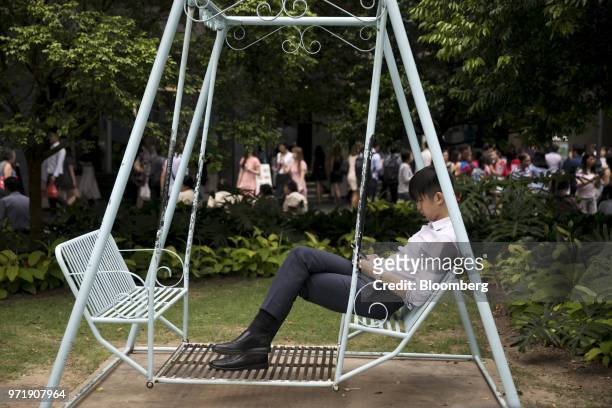 Man uses a mobile phone while sitting on a swing in Singapore, on Tuesday, June 12, 2018. U.S. President Donald Trump and North Korean leader Kim...