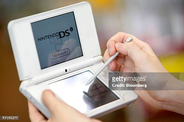 Woman tries out Nintendo Co.'s DSi LL handheld game console at a game store in Soka City, Saitama Prefecture, Japan, on Monday, March 1, 2010....