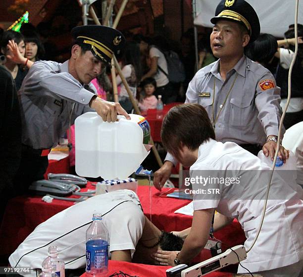 Police officer pours cool water on a man as he is treated by a nurse in a hospital in Taiwan's southern Chiayi city on February 28, 2010 for burns...