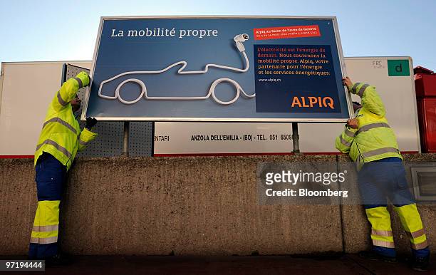 Employees install a sign for the clean energy provider Alpiq Holding AG prior to the official opening of the Geneva International Motor Show in...