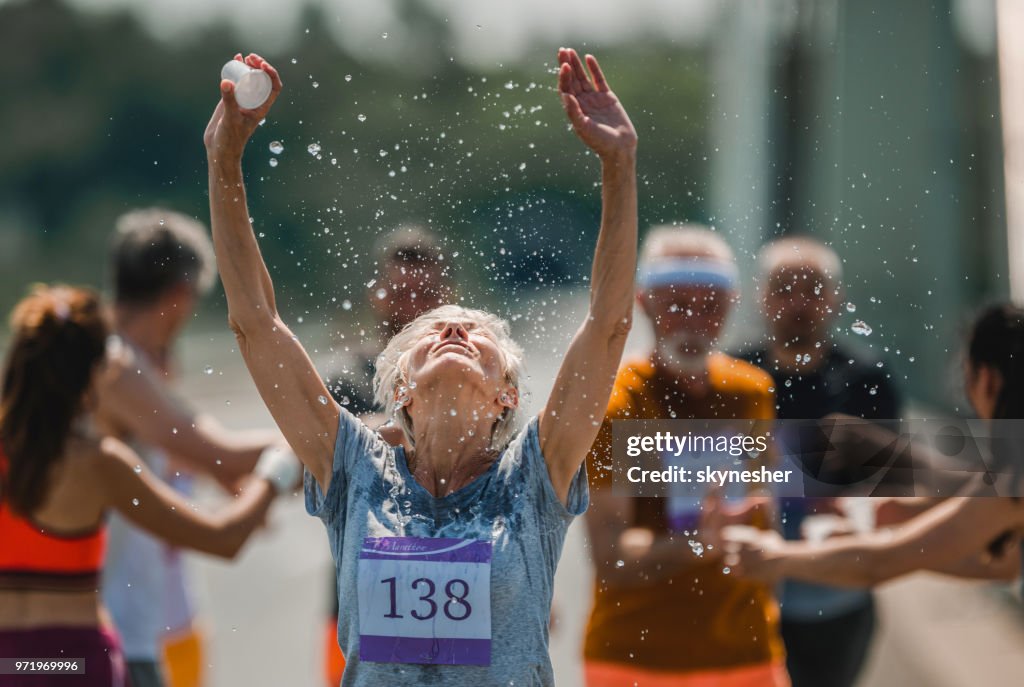 Senior marathonloper vernieuwen zich met water tijdens een race.
