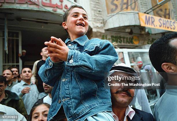 Ramallah, West Bank 5/2/02 A Palestinian man holds his son aloft to get a better view of Palestinian president Yasser Arafat as he and his entourage...