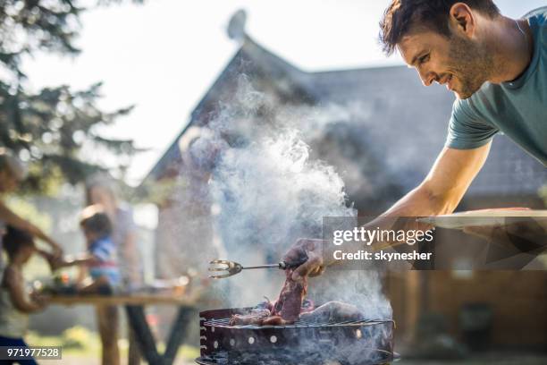 gelukkig man grillen van vlees op een barbecue grill buiten. - barbeque stockfoto's en -beelden