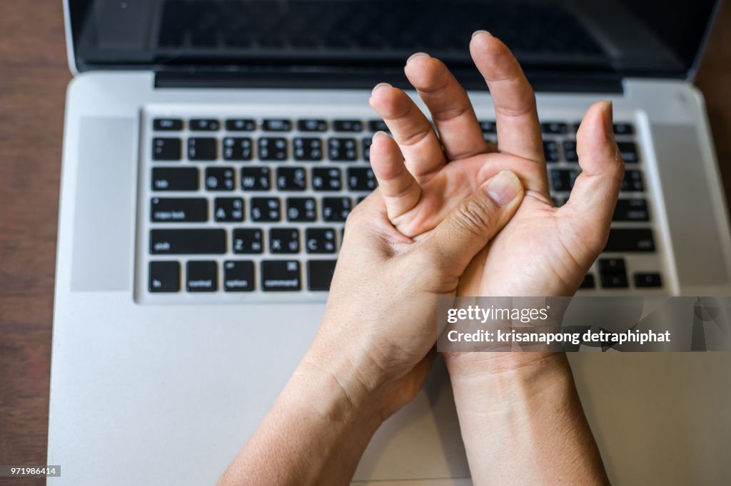 Woman holding her wrist pain from using computer.,Hand pain