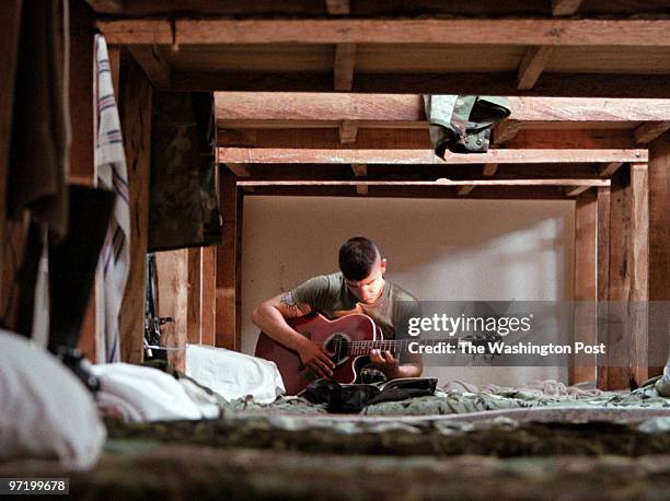 Marines Jahi Chikwendiu/TWP US Marine Garey teaches himself to play a guitar given to him by local boys at Edwin Andrews Airbase in Zamboanga City,...