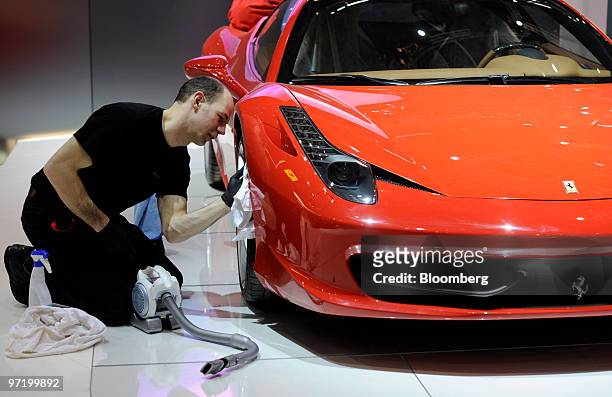 An employee cleans a Ferrari automobile prior to the official opening of the Geneva International Motor Show in Geneva, Switzerland, on Monday, March...