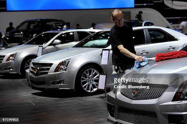 An employee cleans Cadillac automobiles prior to the official opening of the Geneva International Motor Show in Geneva, Switzerland, on Monday, March...