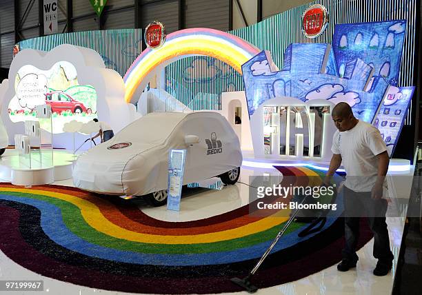 An employee cleans the Fiat stand prior to the official opening of the Geneva International Motor Show in Geneva, Switzerland, on Monday, March 1,...