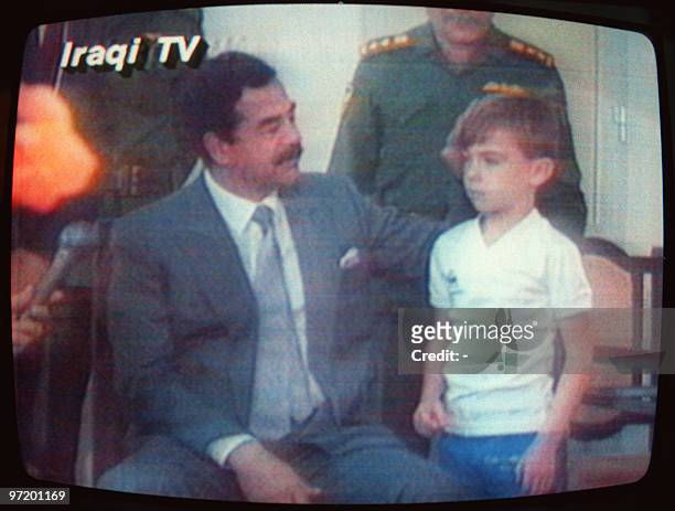 This photo taken from Iraqi TV shows Iraqi President Saddam Hussein patting Stuart Lockwood a young British boy on the head 23 August 1990 in Baghdad...