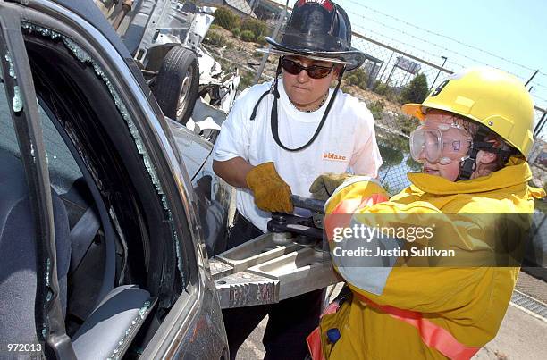 San Francisco firefighter Delainya Salstrand assists 16-year-old Caitlin Walsh with the Jaws-of-Life at Camp Blaze July 10, 2002 in Oakland,...