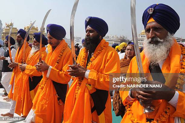 Indian Sikh devotees known as Punj Pyara hold swords as they escort the procession from Sri Akal Takhat at the Golden Temple in Amritsar on March 1...