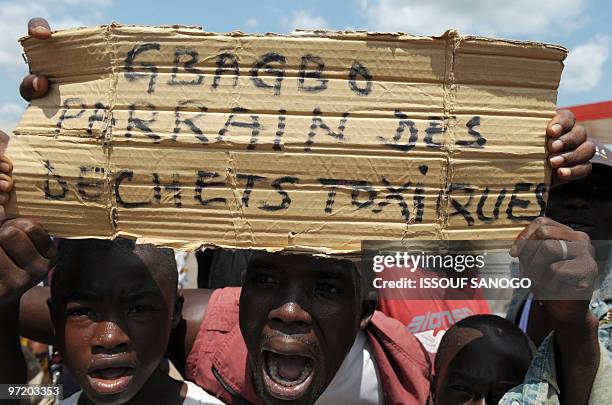 Ivory Coast's opposition supporters hold a placard reading "Gbagbo godfather of toxic waste" as they protest in a street of the central town of...
