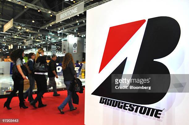 Employees pass a Bridgestone logo prior to the official opening of the Geneva International Motor Show in Geneva, Switzerland, on Monday, March 1,...