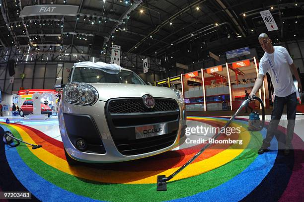 An employee vacuums in front of a Fiat Doblo automobile at the Fiat SpA stand prior to the official opening of the Geneva International Motor Show in...