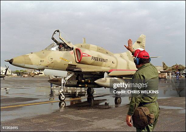 Kuwaiti airfield worker waves to a departing of a Kuwaiti Air Force A-4 US-made Skyhawk jet fighter pilot 24 January 1991 leaving the Al Hasra air...