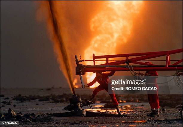 Red Adair fire fighting crew work 29 March 1991 on a blown-out well damaged by retreating Iraqi soldiers in Al-Ahmadi oil field in southern Kuwait....