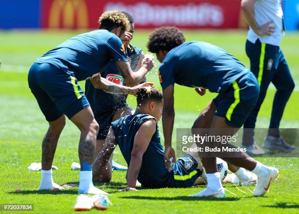 Neymar Jr and Willian of Brazil smash eggs on Philippe Coutinho of Brazil as a birthday prank during a Brazil training session ahead of the FIFA...