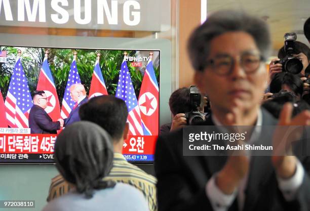 Man claps his hands while watching television news reporting the summit between U.S. President Donald Trump and North Korean leader Kim Jong-Un at...