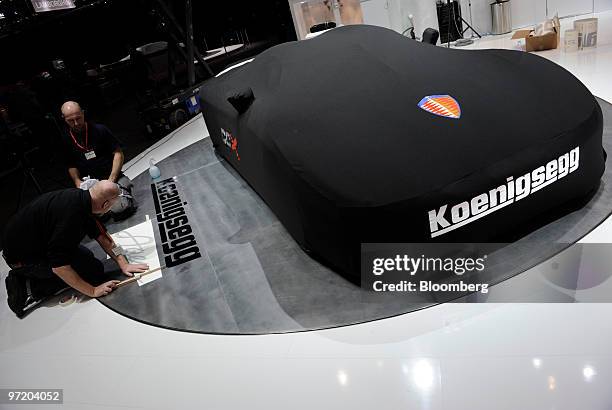 Employees prepare the Koenigsegg stand prior to the official opening of the Geneva International Motor Show in Geneva, Switzerland, on Monday, March...