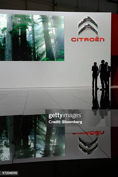 Employees stand in front of the Citroen stand during its installation prior to the official opening of the Geneva International Motor Show in Geneva,...