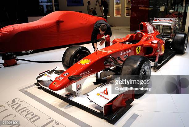 An employee positions a Ferrari Formula One automobile prior to the official opening of the Geneva International Motor Show in Geneva, Switzerland,...