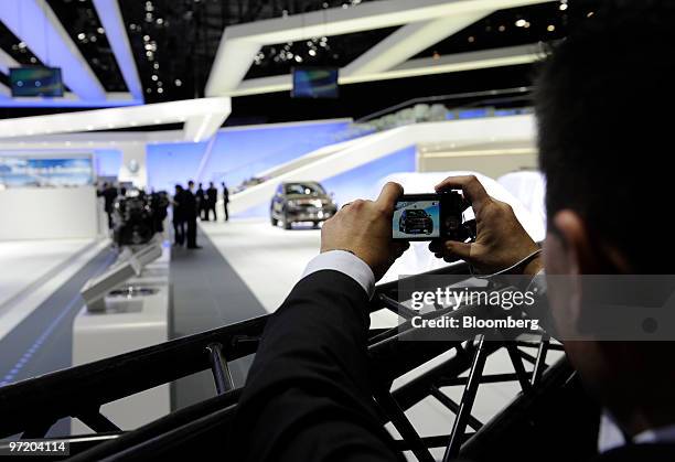 Visitor photographs a Volkswagen automobile prior to the official opening of the Geneva International Motor Show in Geneva, Switzerland, on Monday,...