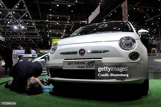 An employee inspects a Fiat 500 automobile prior to the official opening of the Geneva International Motor Show in Geneva, Switzerland, on Monday,...