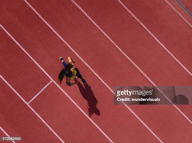 runner donna che ascolta musica e corre su pista sportiva - posizione sportiva foto e immagini stock