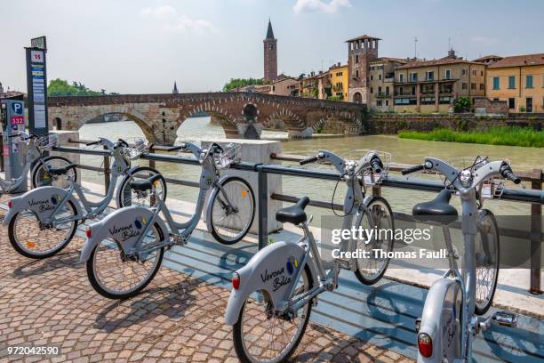 public bicycle hire by the river in verona, italy - adige stock pictures, royalty-free photos & images